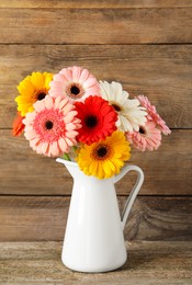 Photo of Bouquet of beautiful colorful gerbera flowers in vase on wooden table