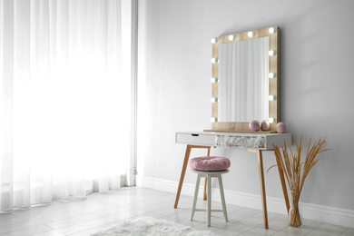 Stylish mirror with lamps near light wall in room