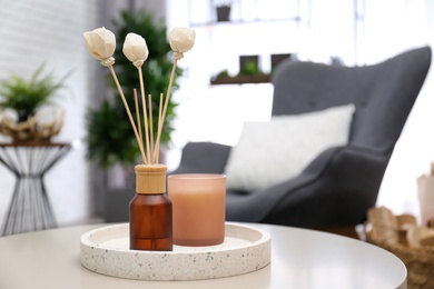 Photo of Reed air freshener and candle on table indoors. Space for text