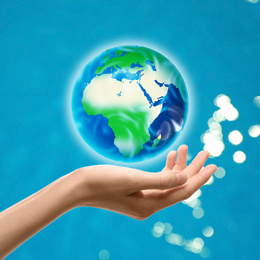 Woman holding icon of Earth on blue background, closeup. Ecology concept