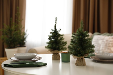 Small fir trees on dining table indoors. Christmas interior design