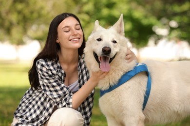 Teenage girl hugging her white Swiss Shepherd dog in park