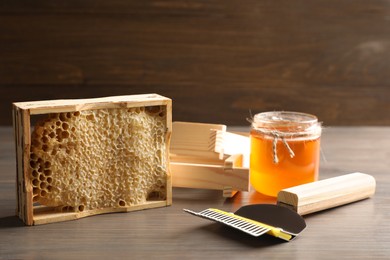 Composition with honeycomb and beekeeping equipment on wooden table