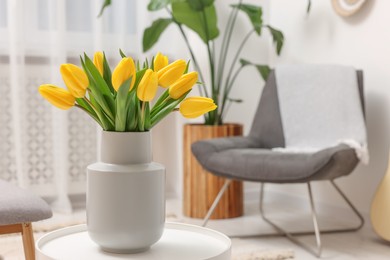 Photo of Spring interior. Bouquet of beautiful yellow tulips on white table in living room, space for text
