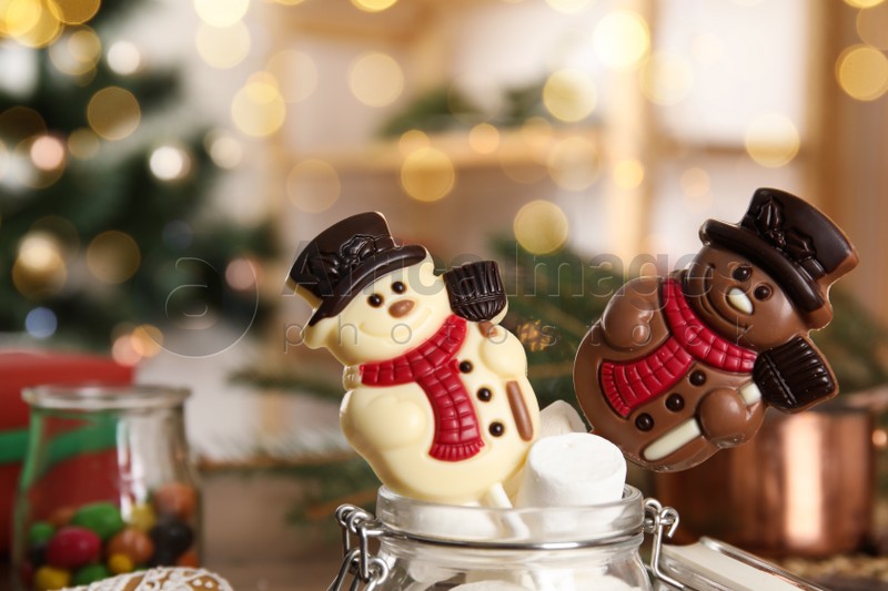 Funny chocolate snowmen candies in glass jar with marshmallows, closeup