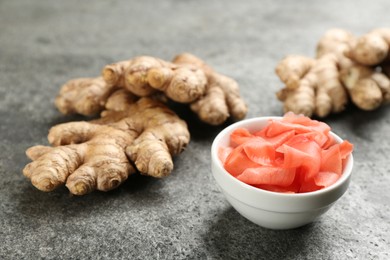 Photo of Spicy pickled ginger and root on grey table, closeup