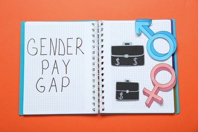 Photo of Gender pay gap. Notebook, paper briefcases with male and female symbols on orange background, top view