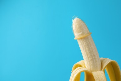 Banana with condom on light blue background, space for text. Safe sex concept