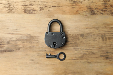 Steel padlock and key on wooden background, top view. Safety concept