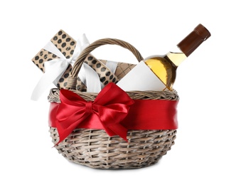 Festive basket with bottle of wine and gifts on white background