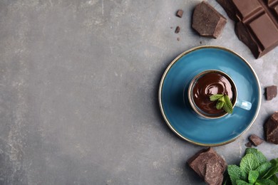 Cup of delicious hot chocolate, chunks and fresh mint on grey table, flat lay. Space for text