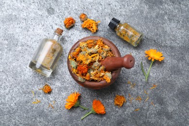 Dry and fresh calendula flowers with tincture on light grey table, flat lay