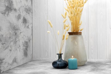 Vases with beautiful dry flowers, candle and double-sided backdrops in photo studio