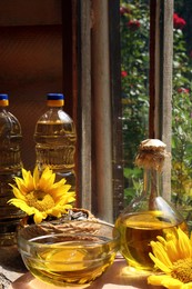 Organic sunflower oil, seeds and flowers on window sill indoors