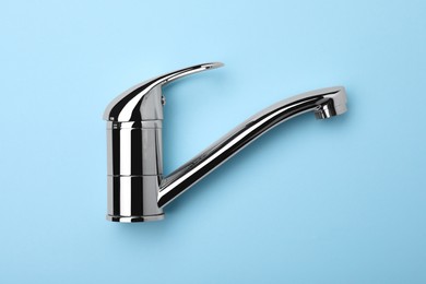 Single handle water tap on light blue background, top view