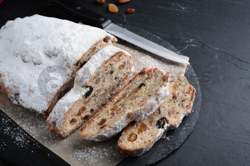 Traditional Christmas Stollen with icing sugar on black table