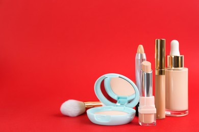 Foundation makeup products on red background, space for text. Decorative cosmetics