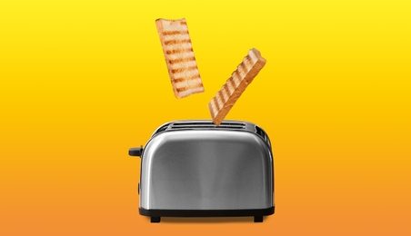 Slices of grilled wheat bread flying out of toaster on color background 
