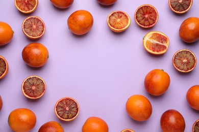 Frame of ripe sicilian oranges on violet background, flat lay. Space for text