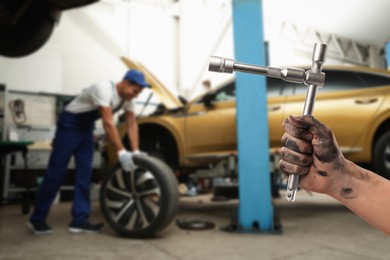 Auto mechanic with instrument near broken down car in repair shop, closeup