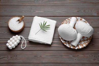 Flat lay composition of herbal bags and spa products on wooden table
