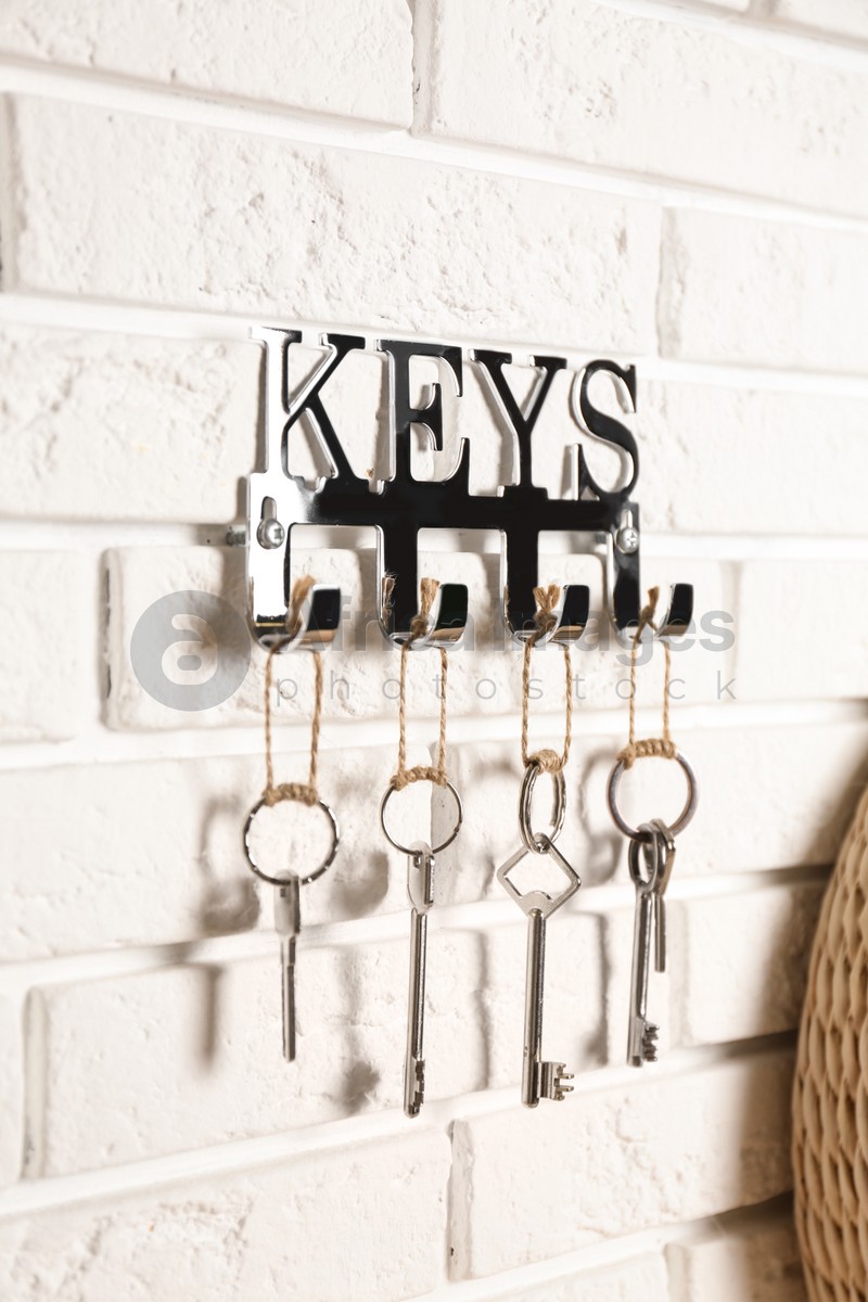 Metal key holder on white brick wall indoors