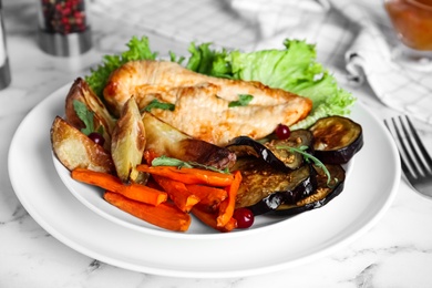 Photo of Delicious cooked chicken and vegetables on white marble table, closeup. Healthy meals from air fryer