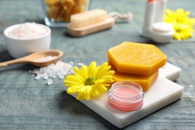 Lip balm, natural beeswax and flower on blue wooden table