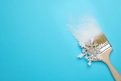 Brush painting with artificial snow on light blue background, top view. Space for text. Creative concept