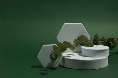 Photo of Product photography props. Podiums of different geometric shapes and plant on green background, space for text