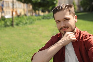 Photo of Smiling man touching his face in park. Space for text