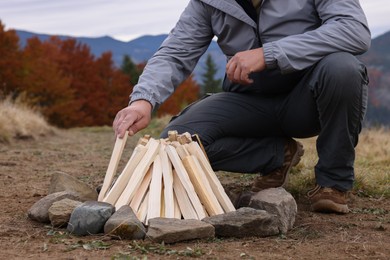 Man making bonfire in mountains, closeup. Camping season