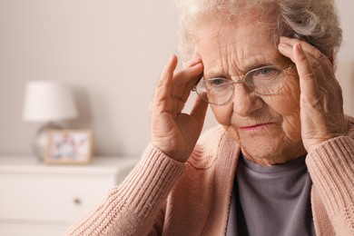 Senior woman with headache in room at home