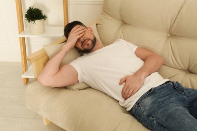 Man suffering from pain in lower right abdomen on sofa at home. Acute appendicitis