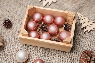 Composition with beautiful Christmas baubles and wooden crate on sacking