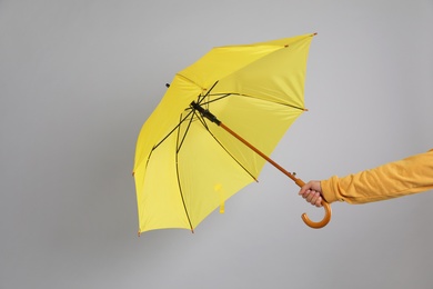 Man holding umbrella caught in gust of wind on grey background, closeup