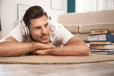 Man with headphones connected to book
on floor at home. Audiobook concept