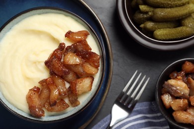 Photo of Potato puree and tasty fried cracklings served on black table, flat lay. Cooked pork lard
