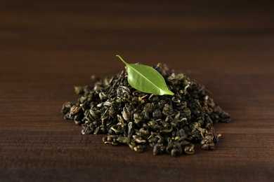Heap of dried green tea leaves on wooden table
