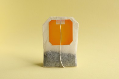 New tea bag with tab on yellow background, closeup