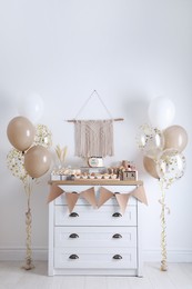 Baby shower party. Different delicious treats on white wooden chest of drawers and decor indoors
