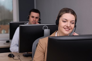 Photo of Young call center operators with headsets working in modern office