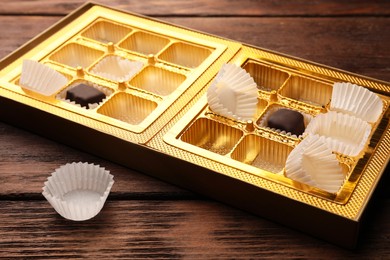 Photo of Partially empty box of chocolate candies on wooden table