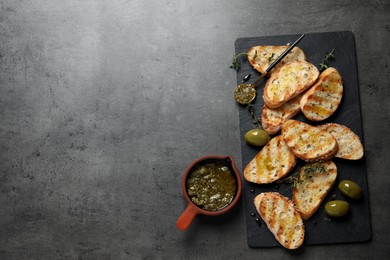 Tasty bruschettas with oil, thyme and olives on grey table, flat lay. Space for text