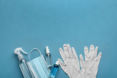 Medical gloves, mask and hand sanitizers on blue background, flat lay. Space for text