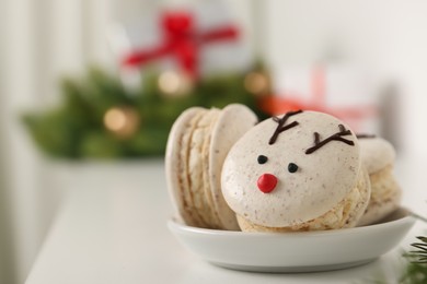 Photo of Tasty reindeer Christmas macarons on white table, closeup. Space for text