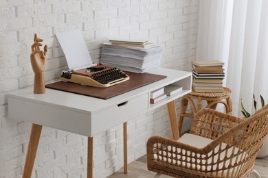 Comfortable writer's workplace interior with typewriter on desk near white brick wall