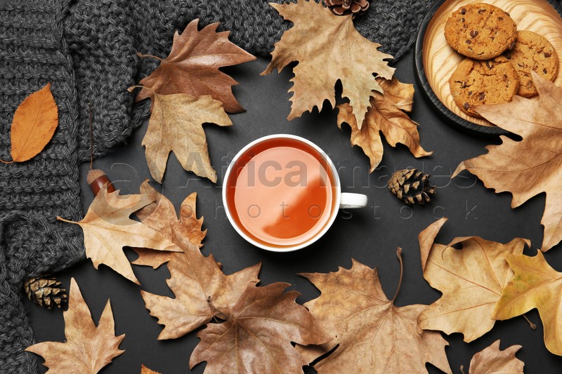 Flat lay composition with hot cozy drink and autumn leaves on dark background