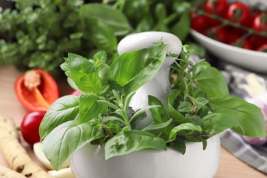 Photo of Mortar with different fresh herbs on table, closeup