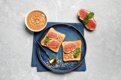 Tasty toasts served with fig, peanut butter and walnuts on white marble table, top view